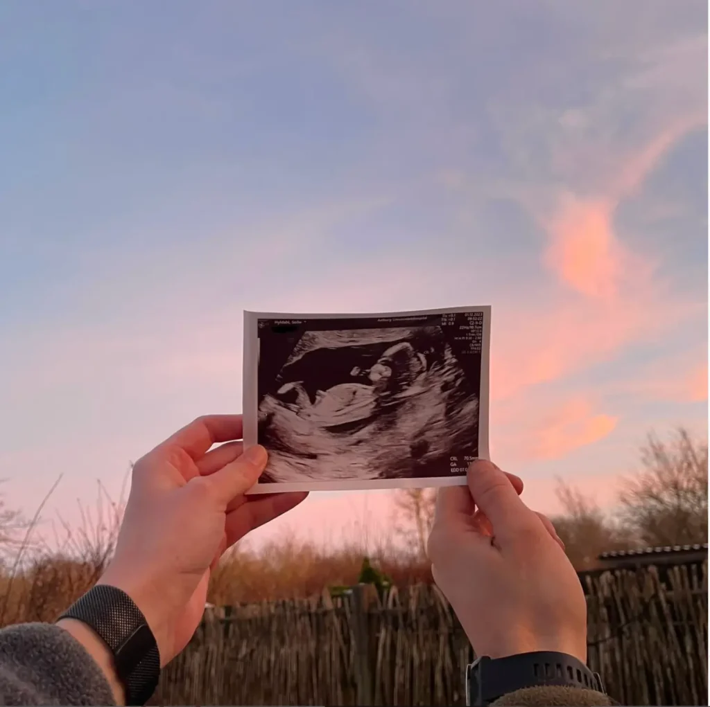 Et par der holder deres hænder på et billede af deres barn