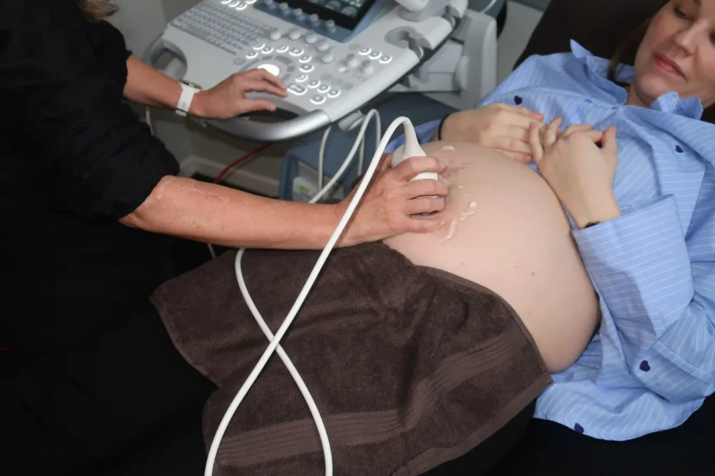 Tæt på graviditetsscanning hvor ultralydsprobe anvendes på gravid mave i klinik